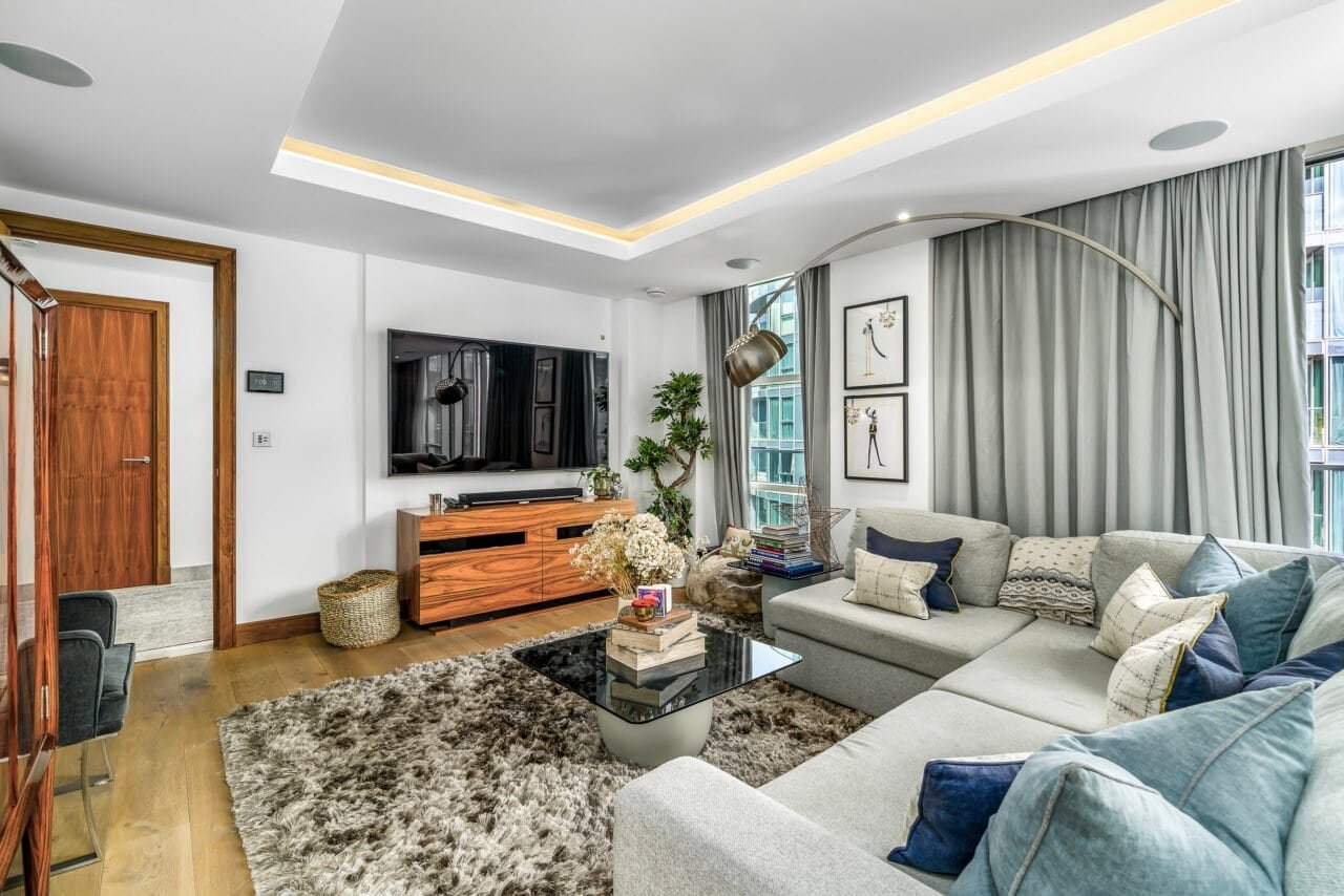 Modern living room with large sofa, flat-screen TV, and stylish decor in a bright apartment.