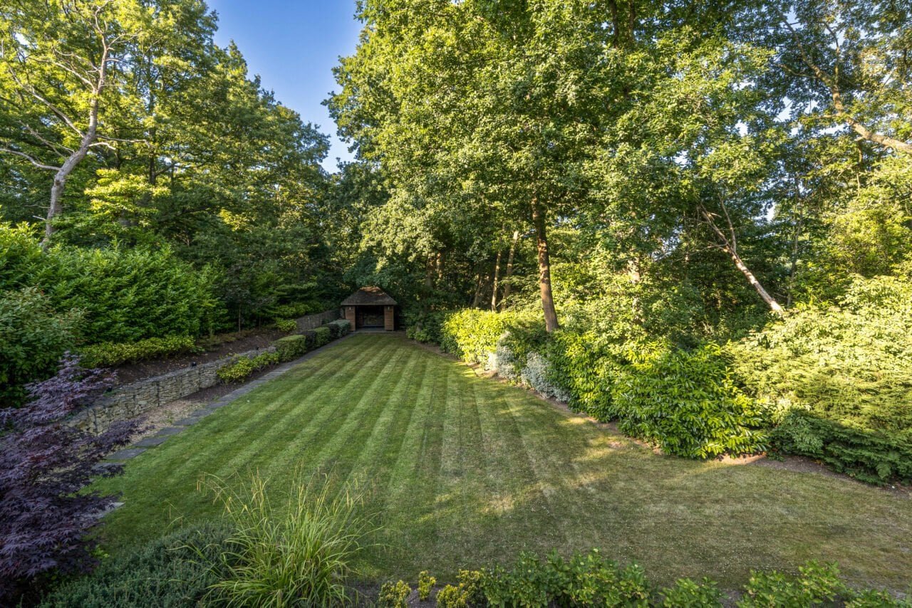 A lush green garden with a well-maintained lawn and surrounding trees and shrubs.