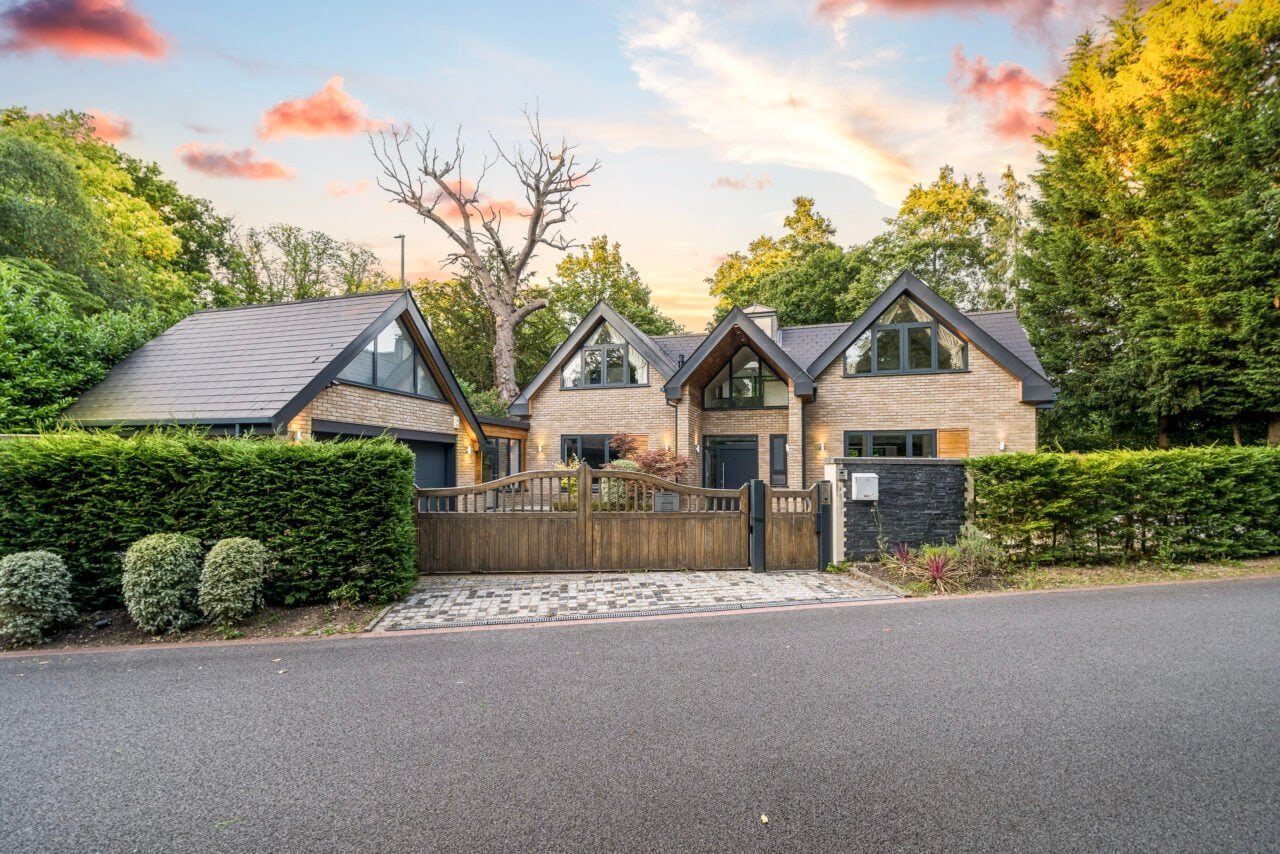Modern detached house with landscaped garden and wooden gate in a suburban neighbourhood.