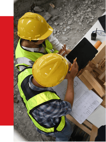 High-visibility construction workers wearing yellow safety helmets and vests reviewing plans and using digital devices at a construction site, emphasizing safety and project management solutions.