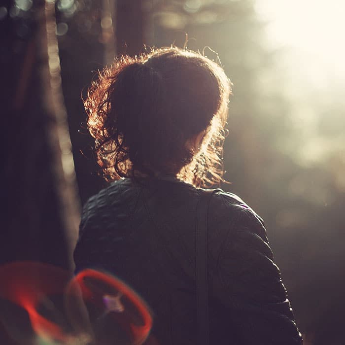 Sunlit woman in a forest during golden hour