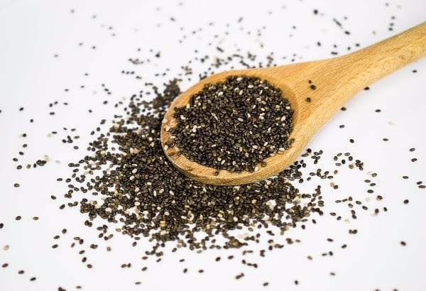 Black chia seeds in a wooden spoon, close-up for superfood and health benefits.