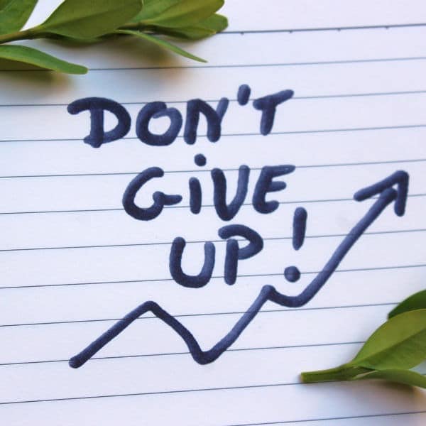 Don't Give Up! Motivational message with an upward trending arrow on lined paper, inspiring perseverance and resilience.