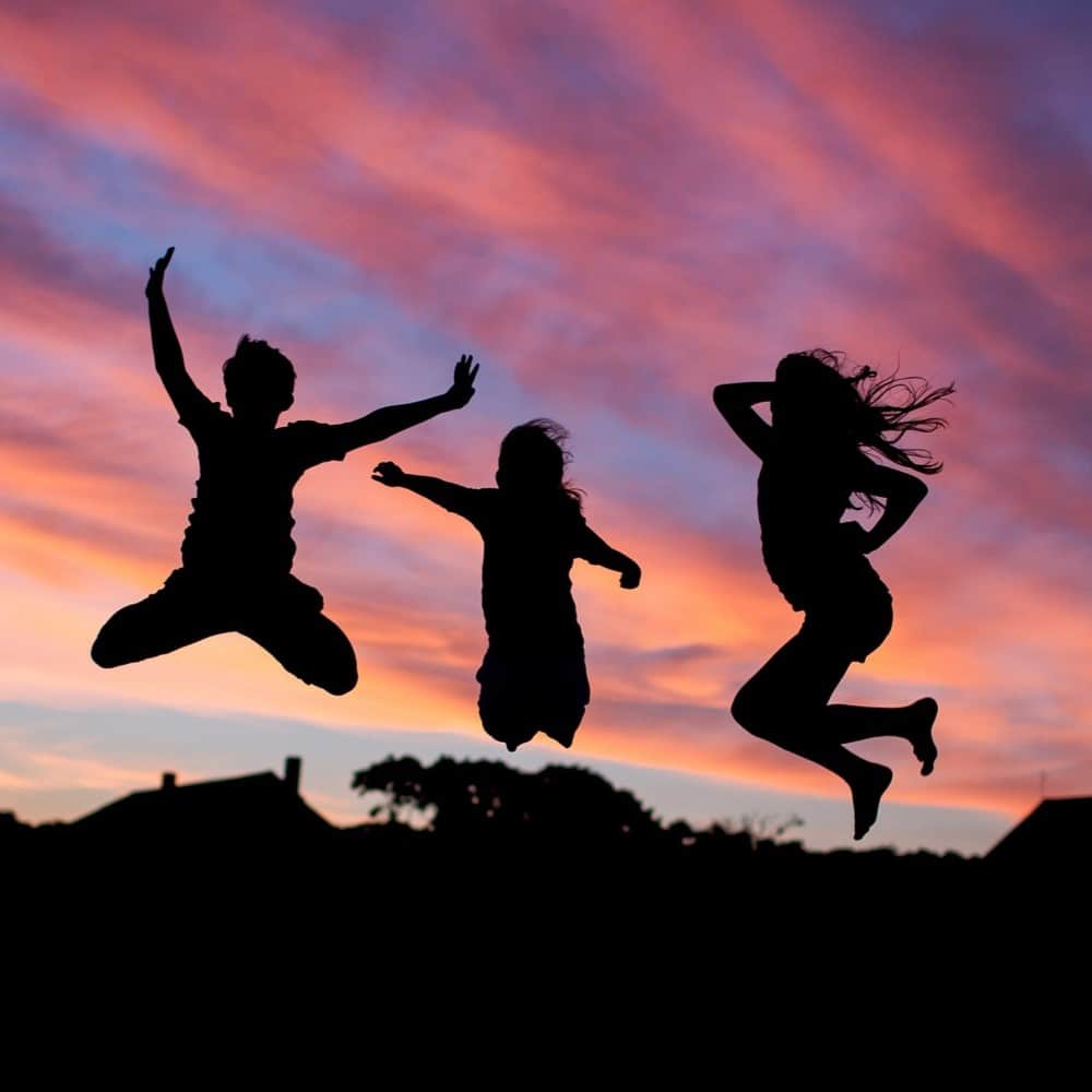 Jumping children at sunset for outdoor play and family fun.