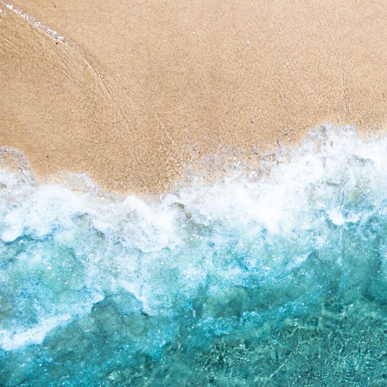 Sea waves crashing onto sandy beach at sunrise, symbolizing calmness and overcoming anxiety.