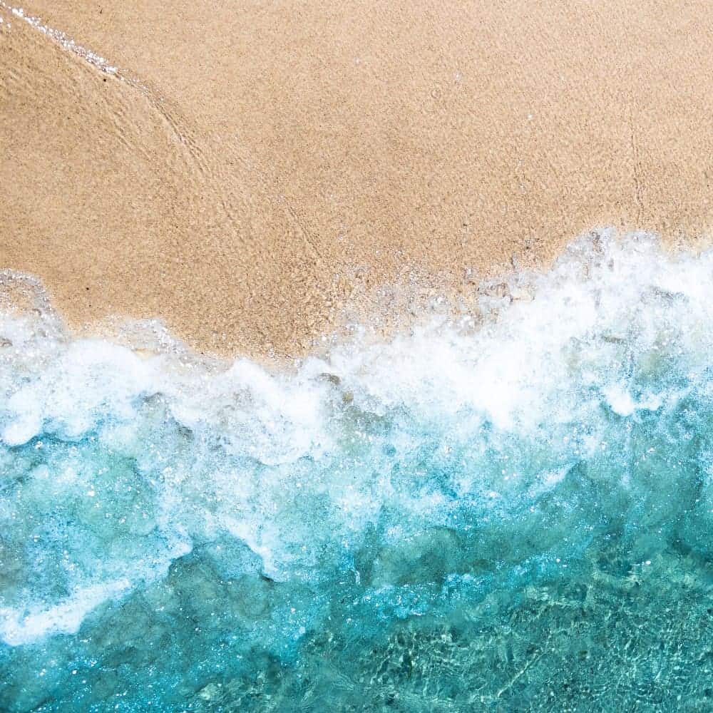 Sea waves crashing onto sandy beach at sunrise, symbolizing calmness and overcoming anxiety.