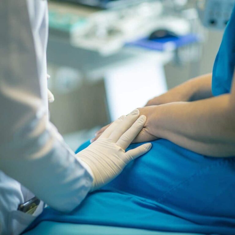 Medical professional examining a patient's arm in a clinical setting.