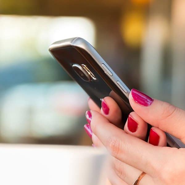Smartphone in hand with pink nails, close-up shot.