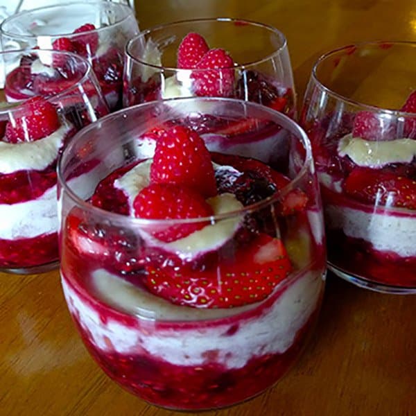 Delicious layered berry parfait with strawberries, raspberries, and cream in elegant glasses.