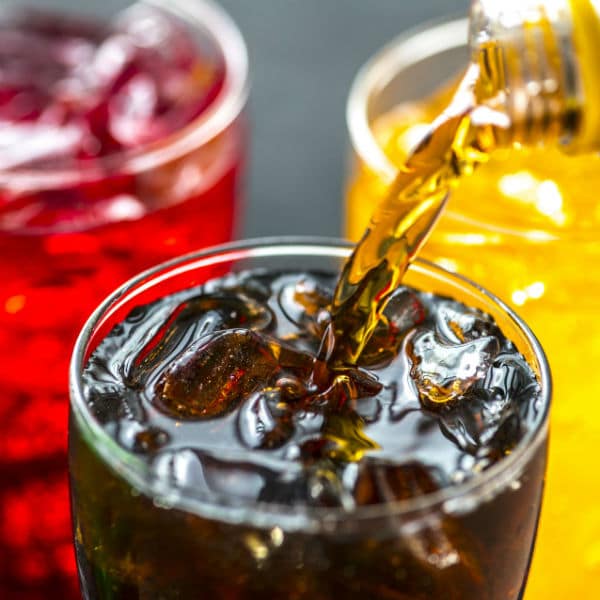 Assorted colorful sodas with ice in glasses, refreshing drinks for summer.