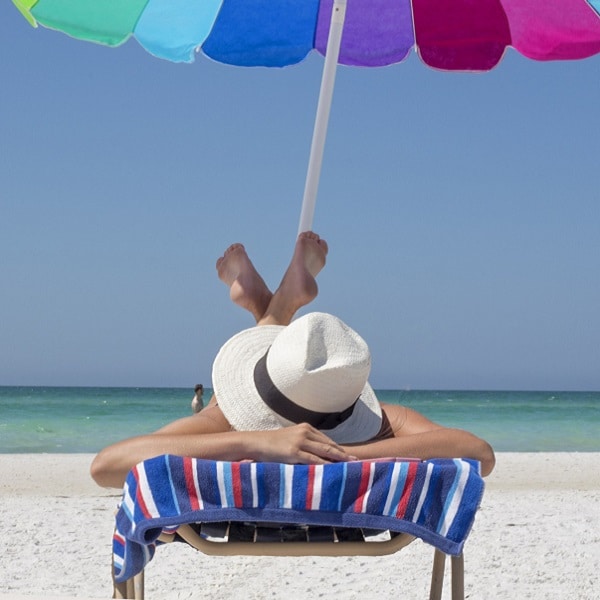 Woman relaxing on a beach chair under a colorful umbrella.