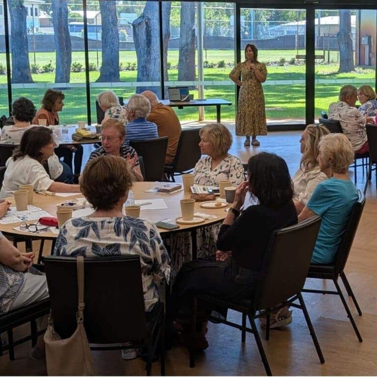 Women attending a community event or workshop in a spacious, well-lit room with large windows.