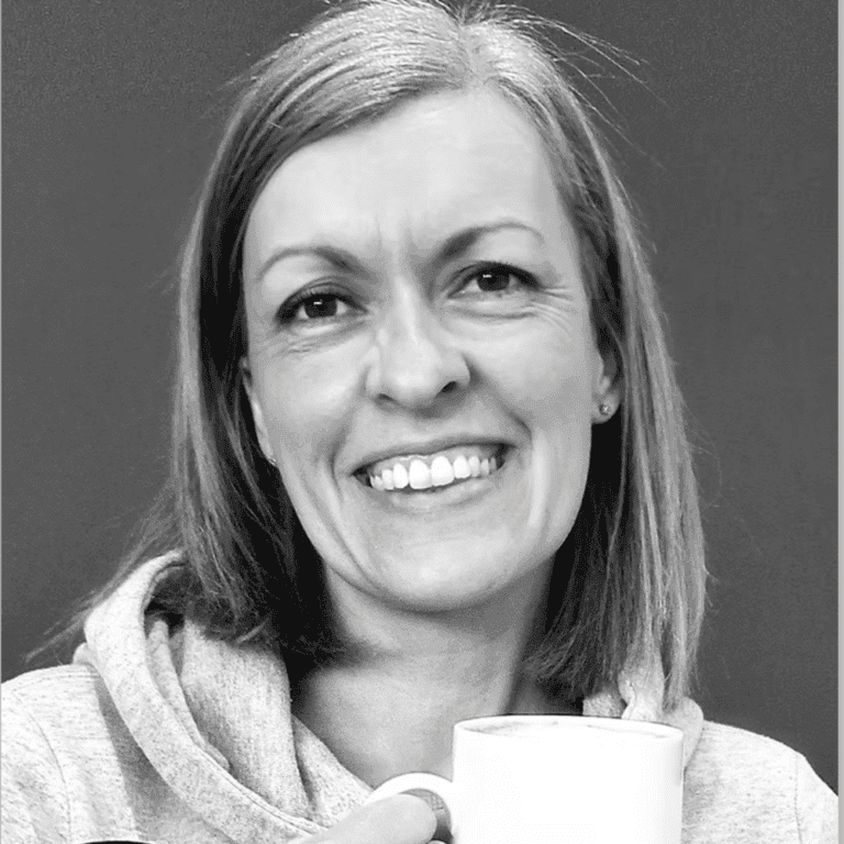 Woman smiling while holding a coffee mug, promoting Raw Horizons' cozy atmosphere.