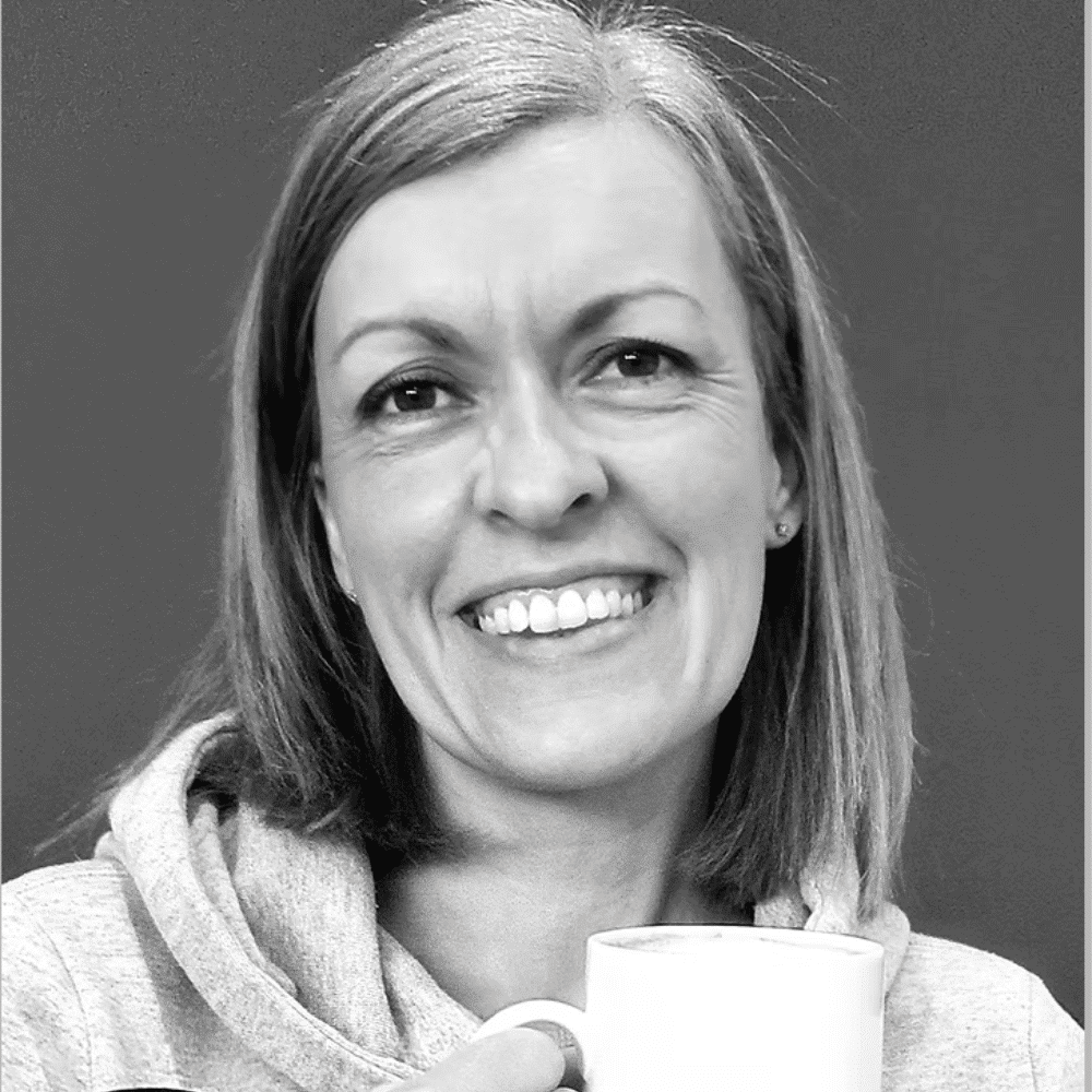 Woman smiling while holding a coffee mug, promoting Raw Horizons' cozy atmosphere.