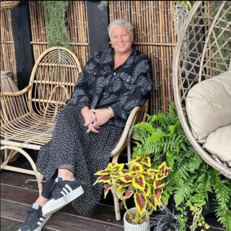 Woman sitting on a wicker chair in a lush garden setting at Raw Horizons.
