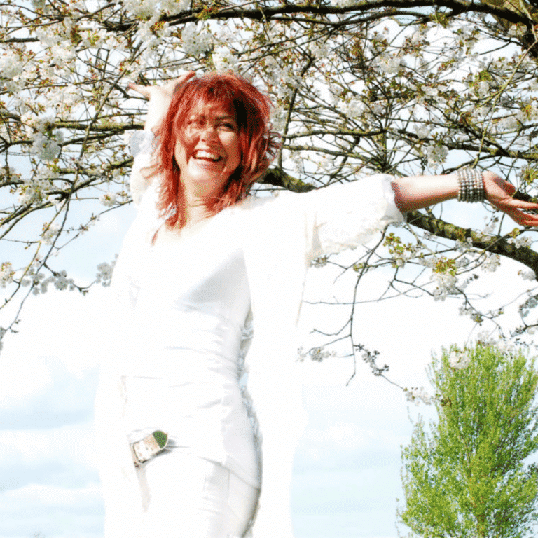 Dr Claire Maguire outdoors under blooming tree, embracing tranquility and mindfulness.