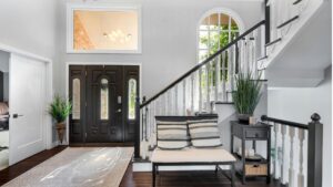 Interior home entry with staircase, black front door, and stylish decor.