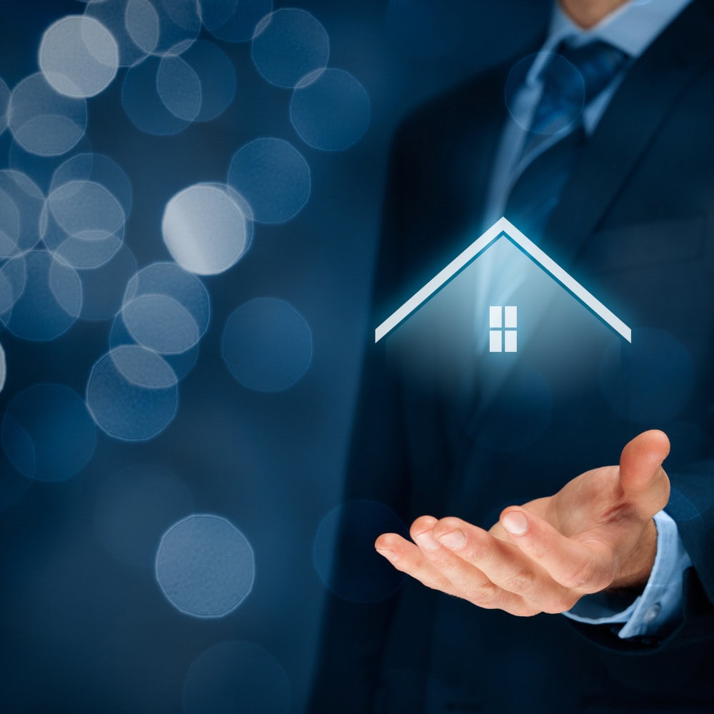 1. Businessman in suit holding holographic house icon representing real estate, property management, and home ownership concepts.