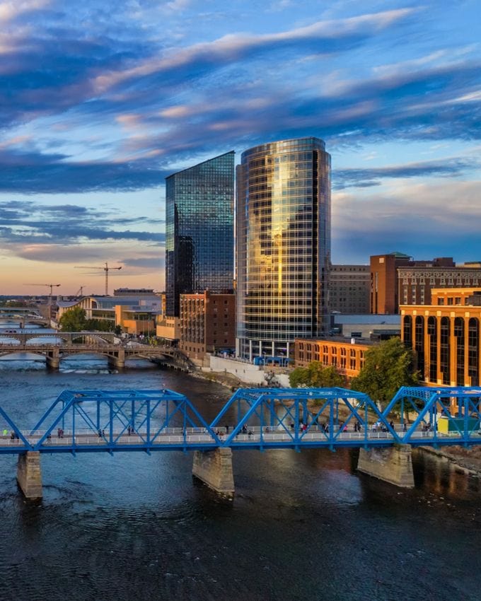 Modern downtown skyline with sleek glass skyscrapers and a vibrant blue bridge over a river, showcasing urban development and architecture.