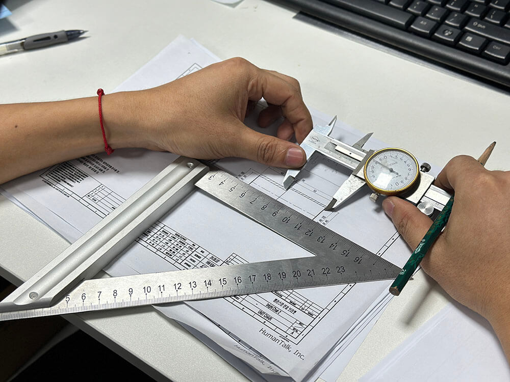 Dial caliper and measuring tools used over a technical component drawing