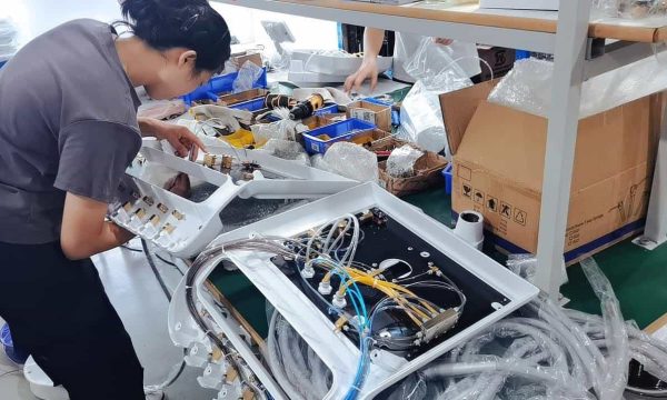 Worker assembling dental chair side unit with internal tubing and valves