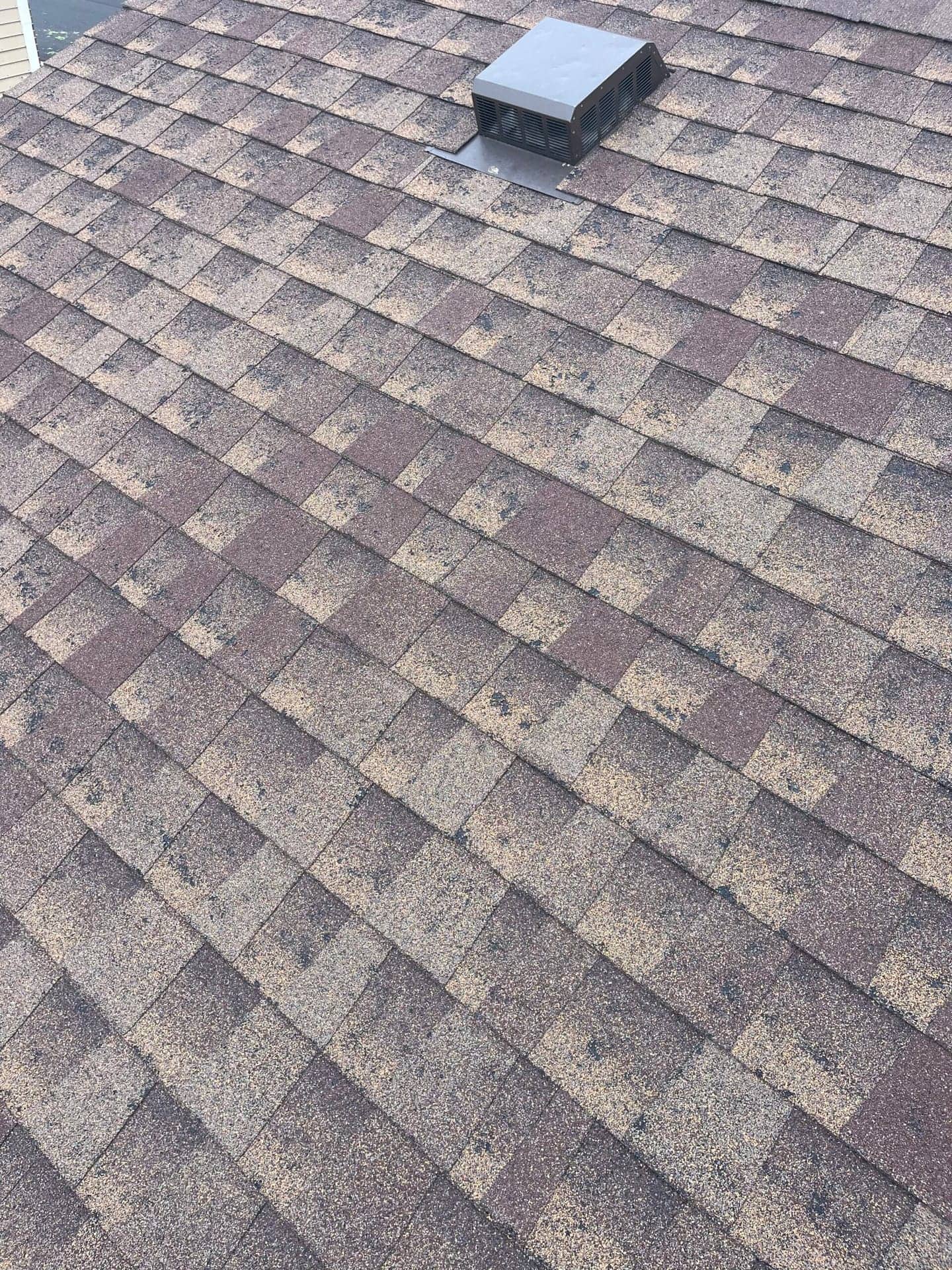 Close-up of asphalt shingles damaged by hail on a residential roof in Aurora, Colorado
