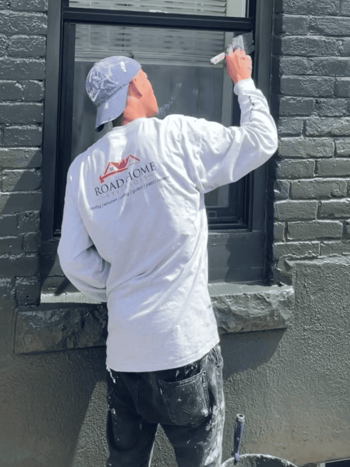 Painter applying fresh exterior paint to a home’s siding