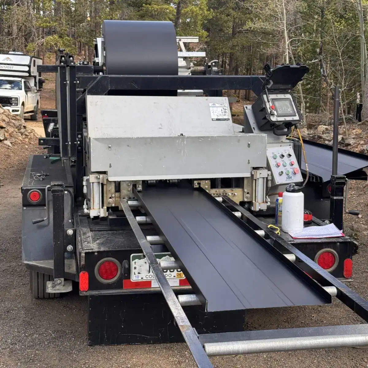 Portable standing seam metal roofing machine fabricating metal roof panels for a residential roofing project in Colorado