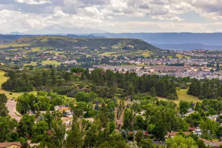 Residential neighborhoods in Castle Pines Colorado with rolling hills, mature trees, open space, and Front Range mountain views.
