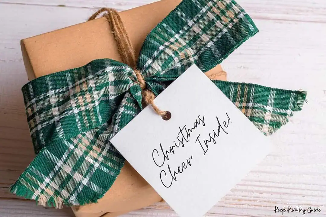 200+ Christmas Quotes and Sayings for Crafts (Free Printable) 6 Green plaid ribbon on gift box with Christmas tag.