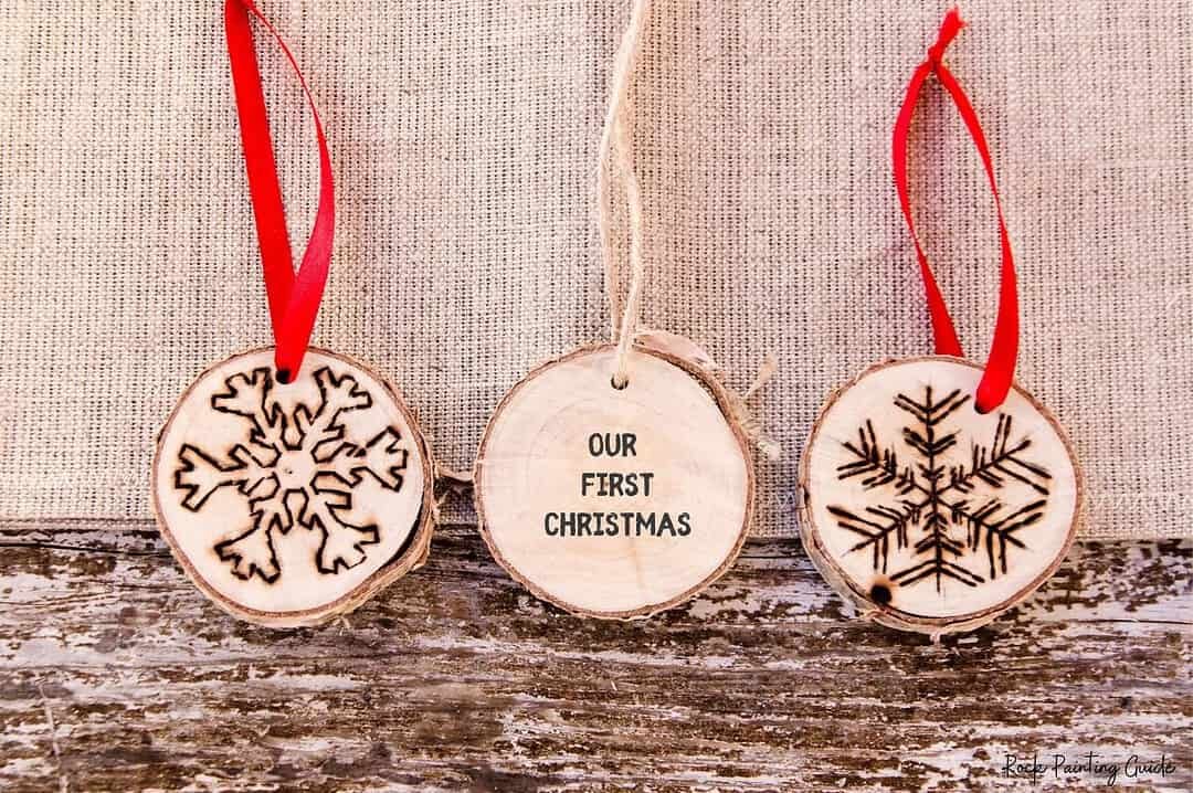 200+ Christmas Quotes and Sayings for Crafts (Free Printable) 5 Wooden Christmas ornaments with snowflake designs and text reading Our First Christmas.