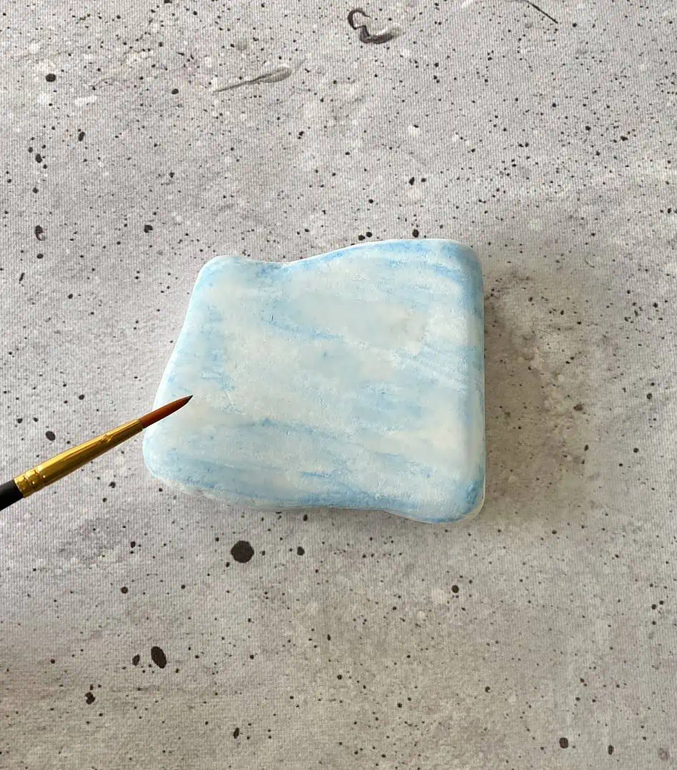 Harry Potter Painted Rocks: A Fun DIY Craft for Potterheads 8 using a brush to paint watercolor on a stone