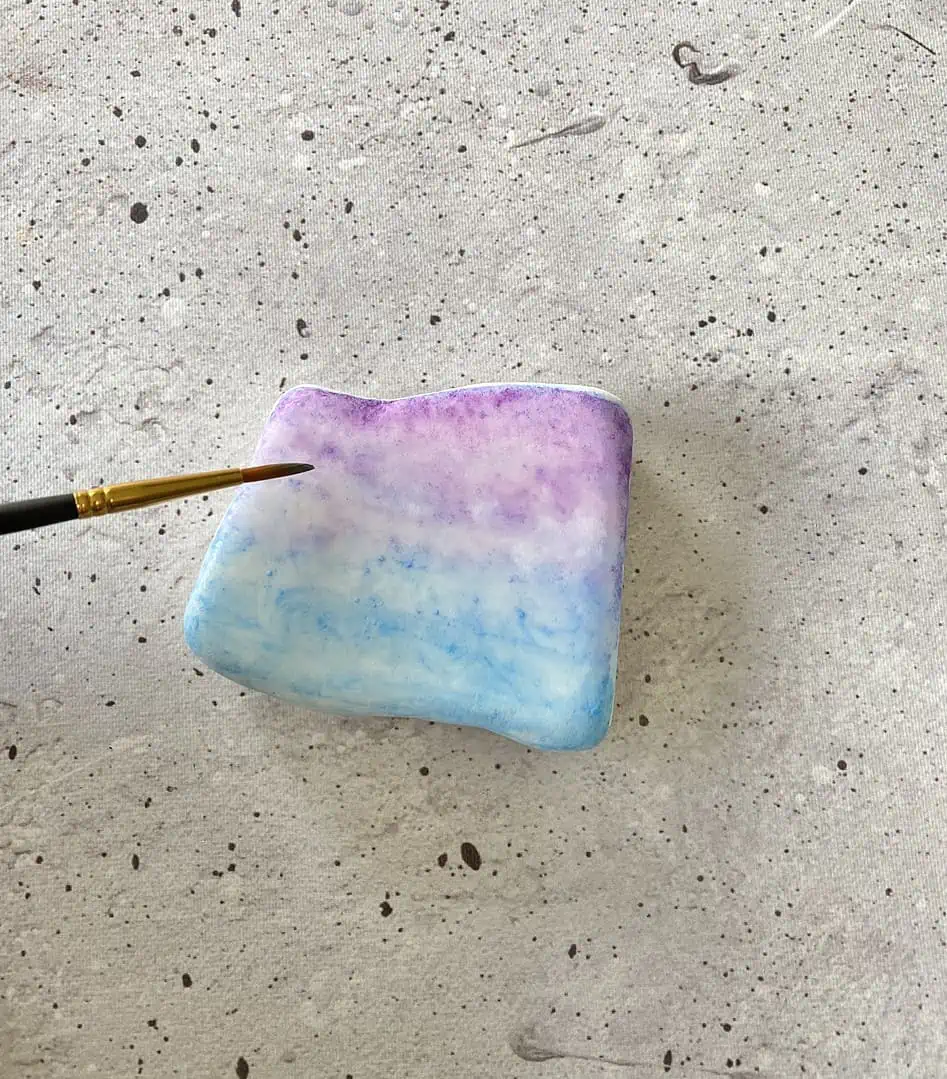 Harry Potter Painted Rocks: A Fun DIY Craft for Potterheads 9 using a brush to paint watercolor on a stone
