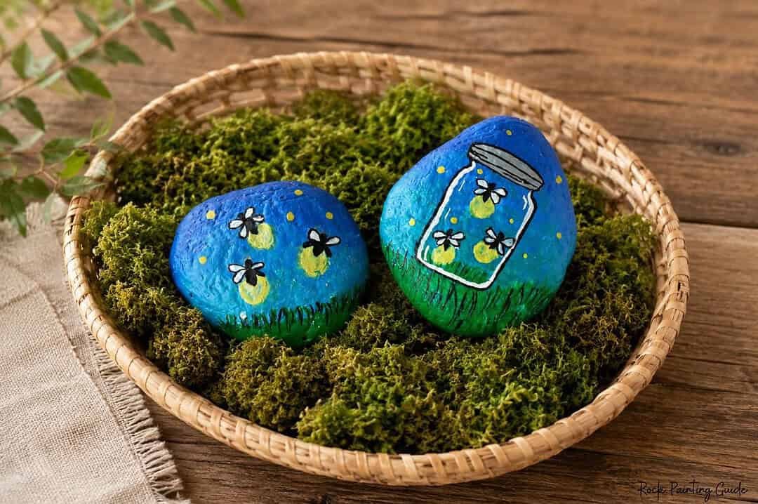 firefly painted rocks laying onto of moss in a basket