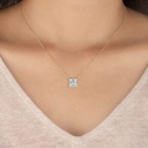 Elegant princess bezel solitaire diamond pendant on delicate gold chain.