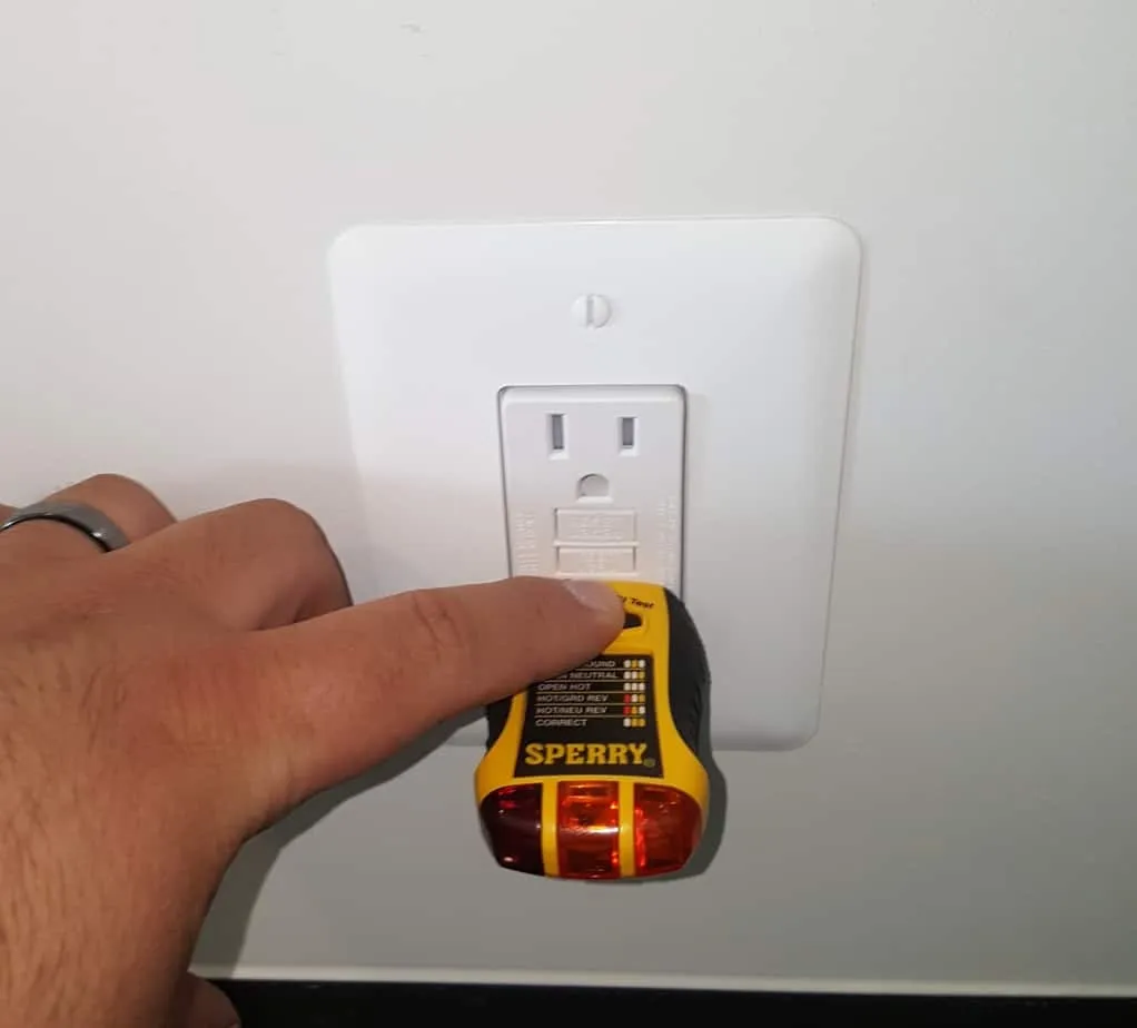 A circuit tester being plugged into a GFCI outlet during an inspection