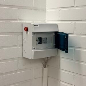 Sähkökeskus seinällä, valkoinen ja kiinnitetty valkoiseen tiiliseinään.