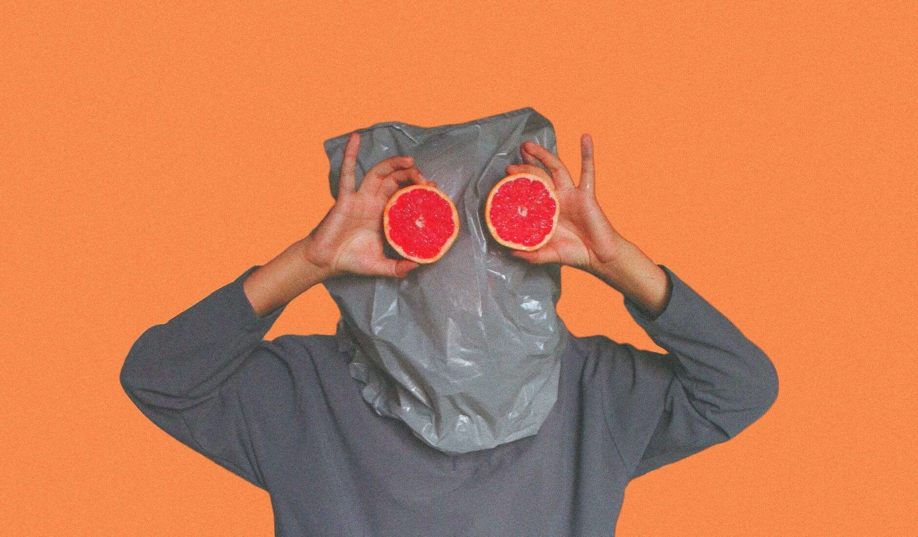Anonymous viewers, person covered with plastic bag on head while holding sliced blood orange
