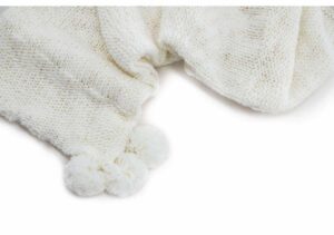 Lapptäcke i stickad ull med pom-pom detalj för mysiga stunder.