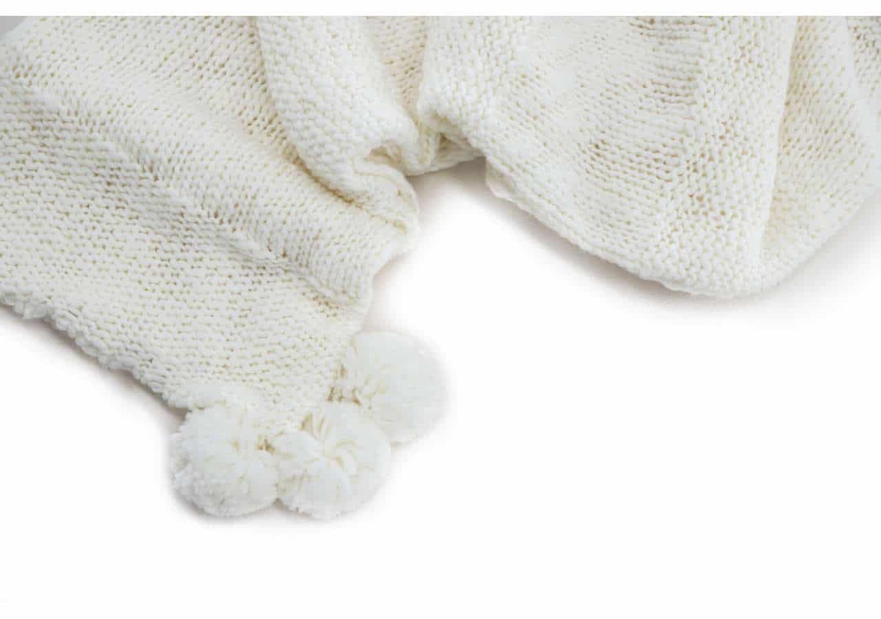 15943-201__04 Lapptäcke i stickad ull med pom-pom detalj för mysiga stunder.