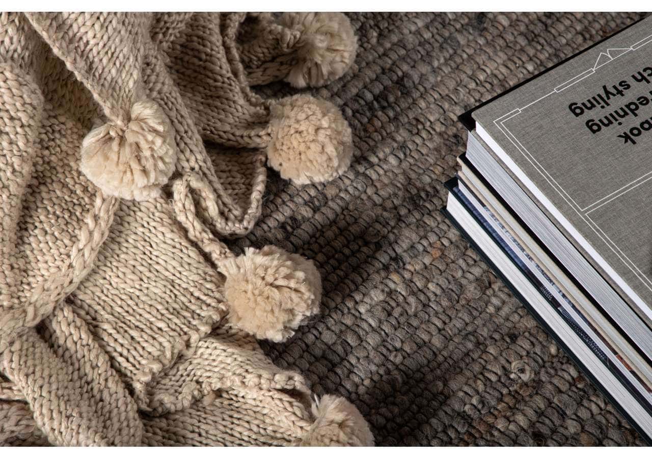 15943-202__003 Mjuk ullfilt med pom-pom detaljer på tyst noga matta, perfekt för en skön sovmiljö.