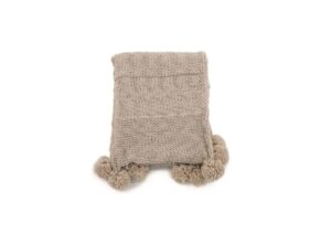Mjukt stickat täcke med pom-pom kanter, perfekt för sängkomfort.