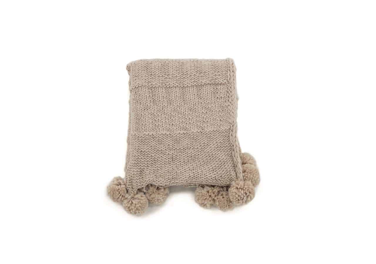 15943-202__02 Mjukt stickat täcke med pom-pom kanter, perfekt för sängkomfort.