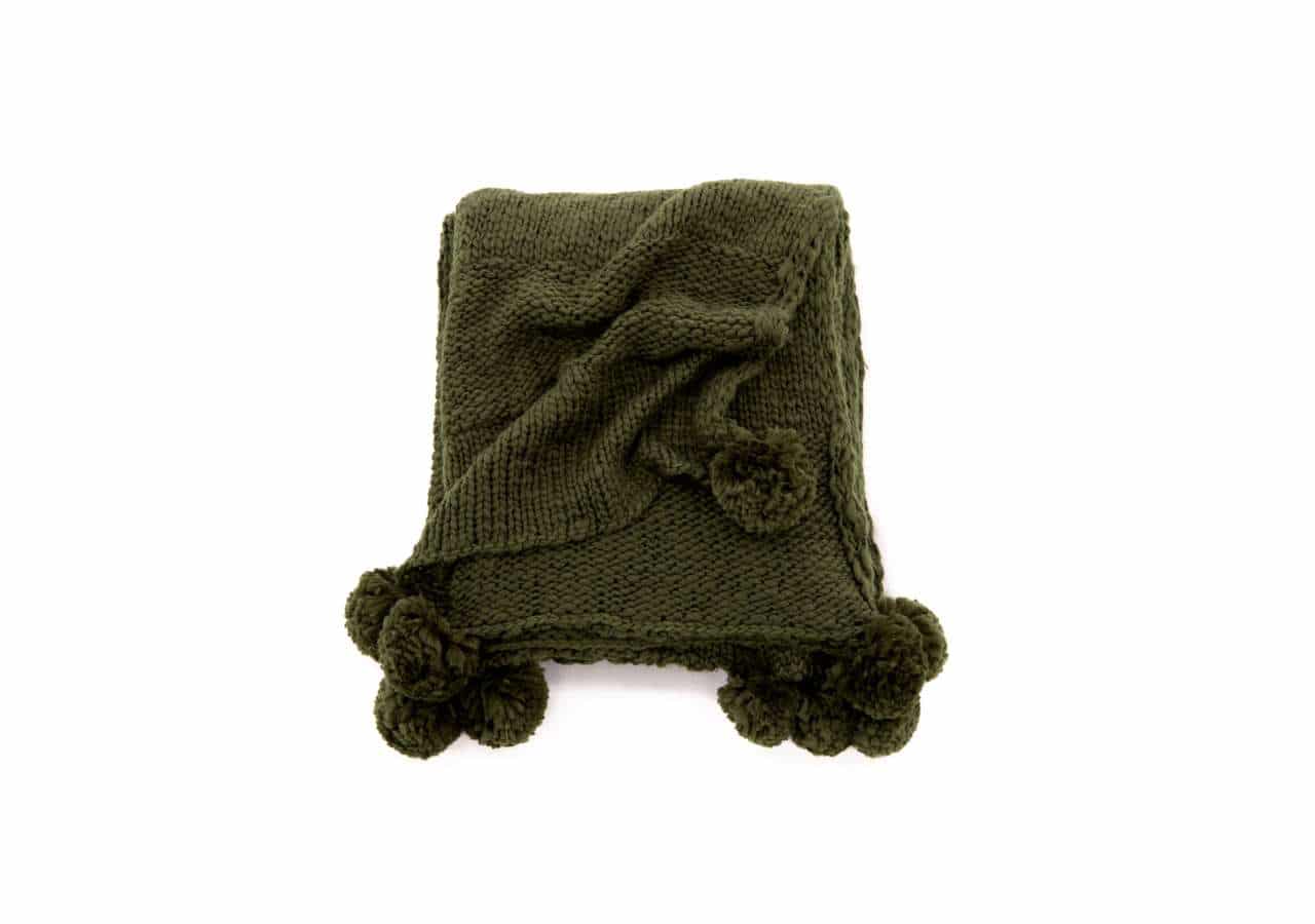 15943-204__03 Mörkgrön stickad filt med pompomkant för mysiga sovstunder.