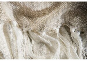 Ljus, handvävd linnetextil med knytdetaljer och spetsdetaljer.