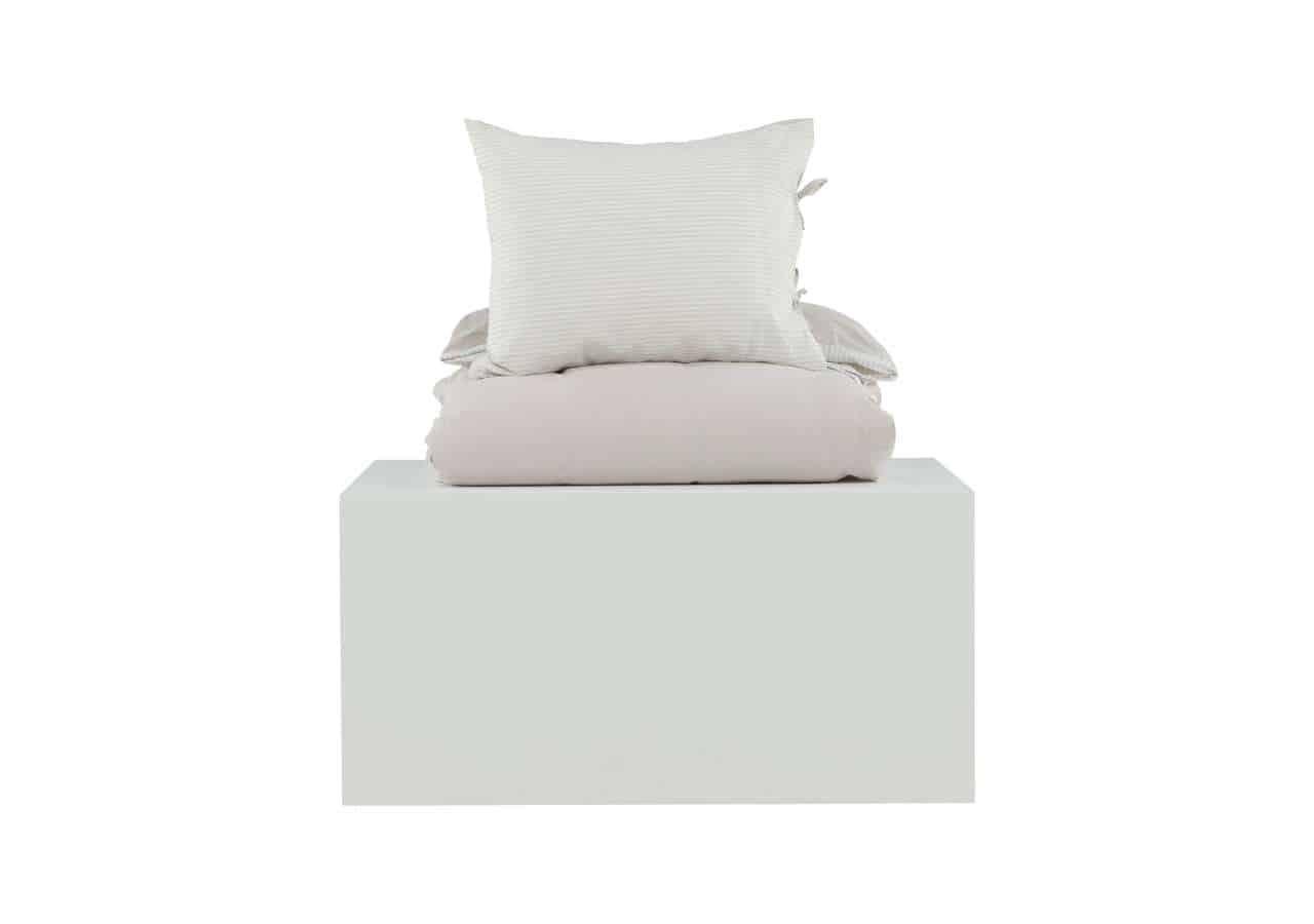 Kuslik säng med vitt sänglinne och kuddar, minimalistisk design för skandinavisk sovrumsmiljö.
