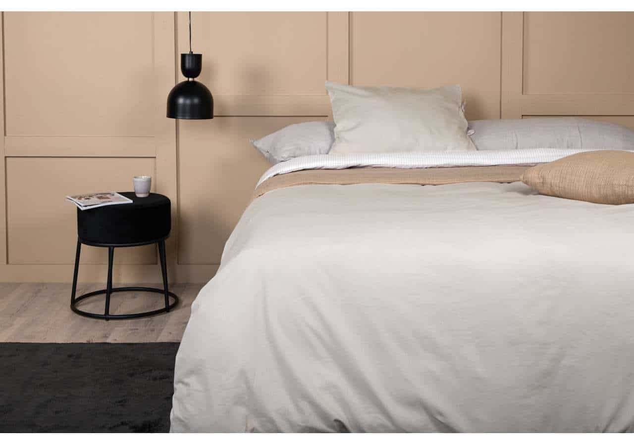 Elegant säng i minimalistisk stil med beige väggpaneler och stilrent nattduksbord.