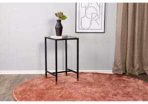 Elegant svart sidobord med blomvas och böcker i modern inredning.