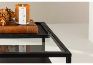 Ljusad fönsterljusreflekterande soffbord i svart metall och glas, elegant och modernt designat.