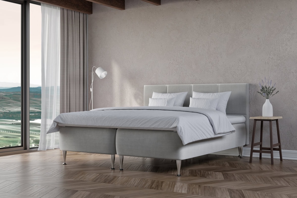 Elegant säng i modern design med bekväma sängkläder och utsikt över landskapet.